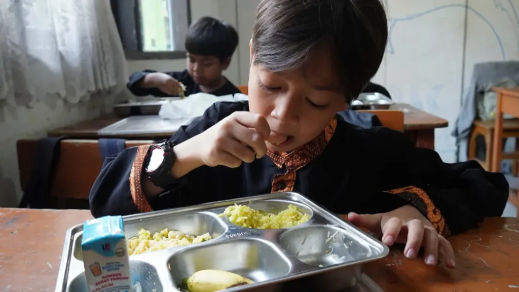 Siswa menerima makanan bergizi gratis, ilustrasi potensi penyebab KLB keracunan MBG